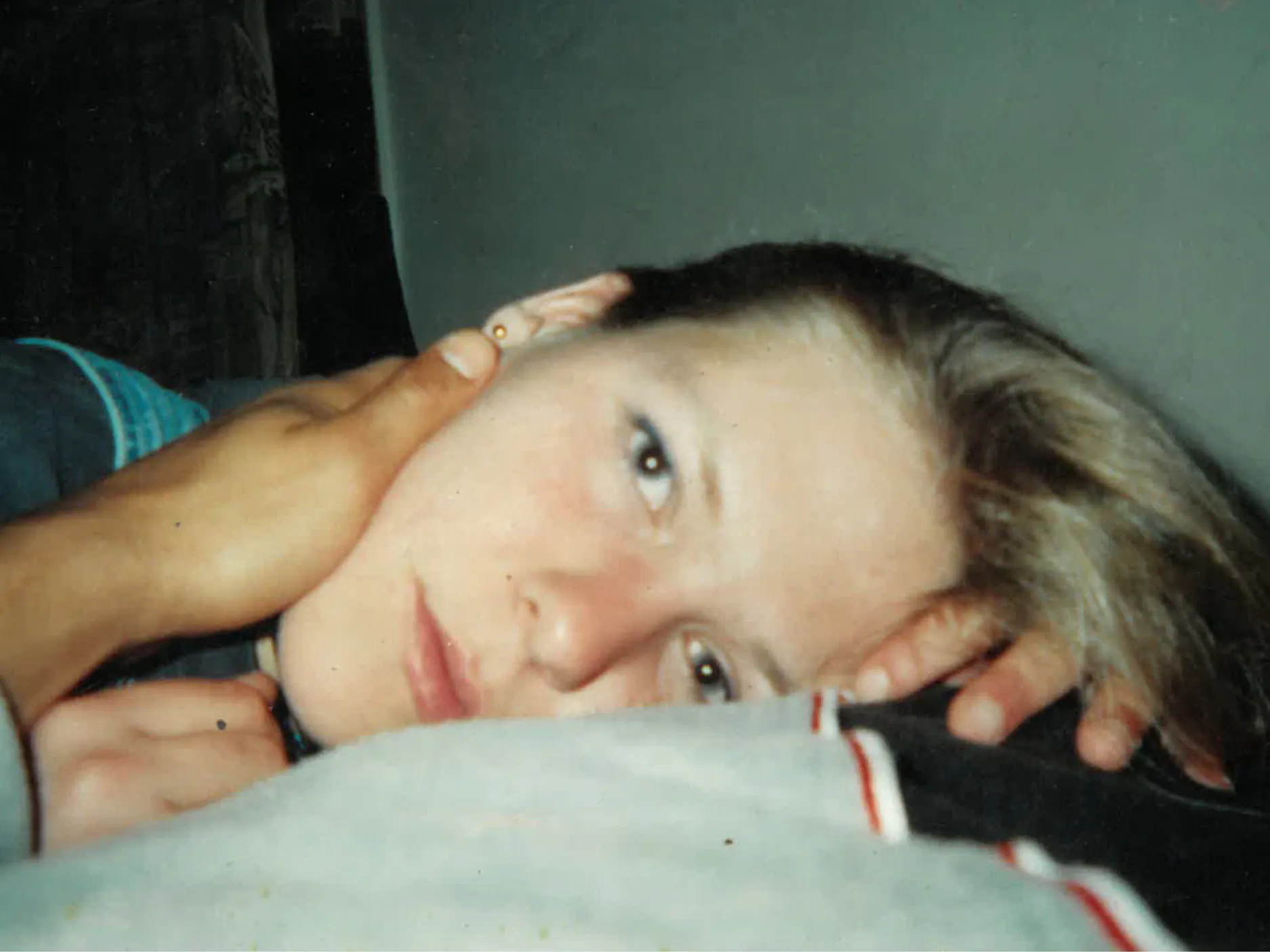 Mlada Tereza Vuk, leži na boku, na njenem obrazu ima roko tisti, ki jo fotografira